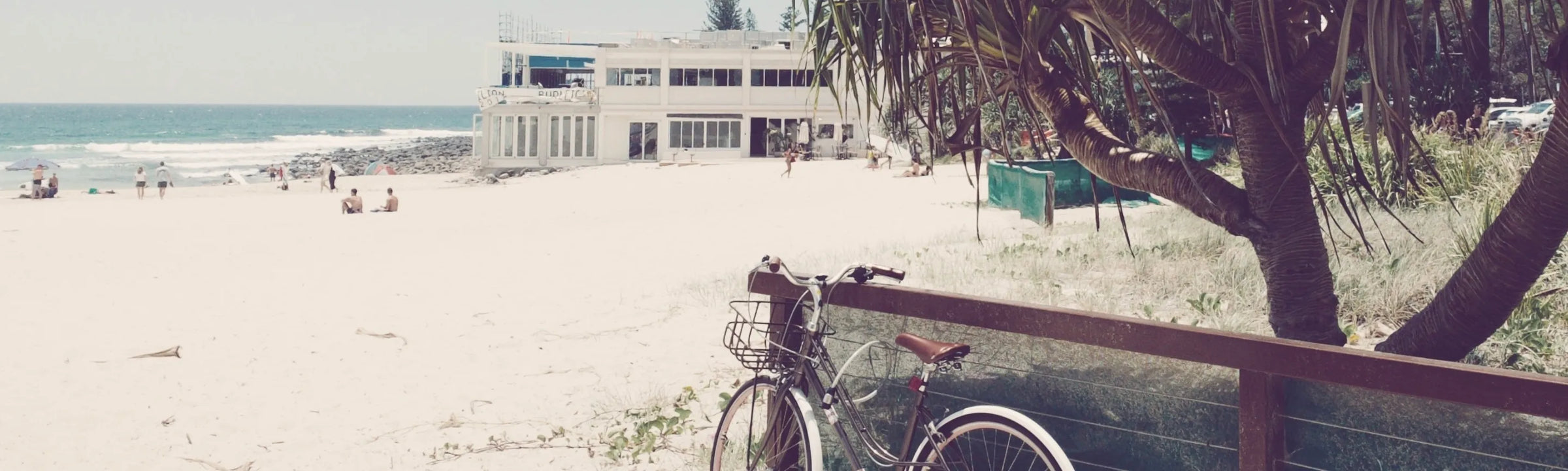 Vintage bicycle leaning against a wooden fence on the Gold Coast beachfront, reflecting the relaxed Australian coastal lifestyle behind the House of Dune brand.