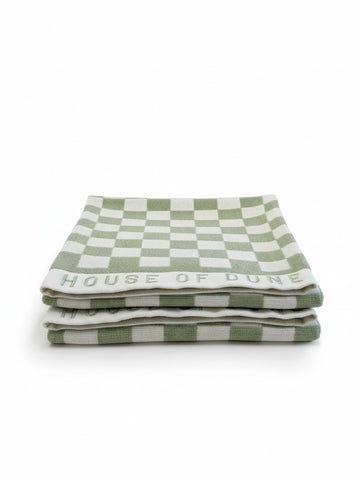 Set of two House of Dune Salted Sage beach towels with green and white checkerboard pattern neatly folded on a white surface.