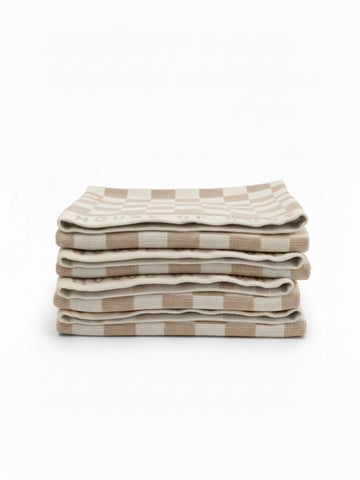 Stack of four House of Dune Sand Drift beach towels featuring a soft beige and white check pattern, folded for a refined coastal look.