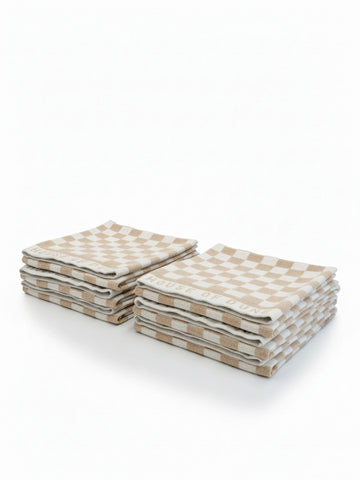 Six House of Dune Sand Drift beach towels folded in two stacks, showing the beige and white checkerboard pattern for a minimalist, coastal aesthetic.