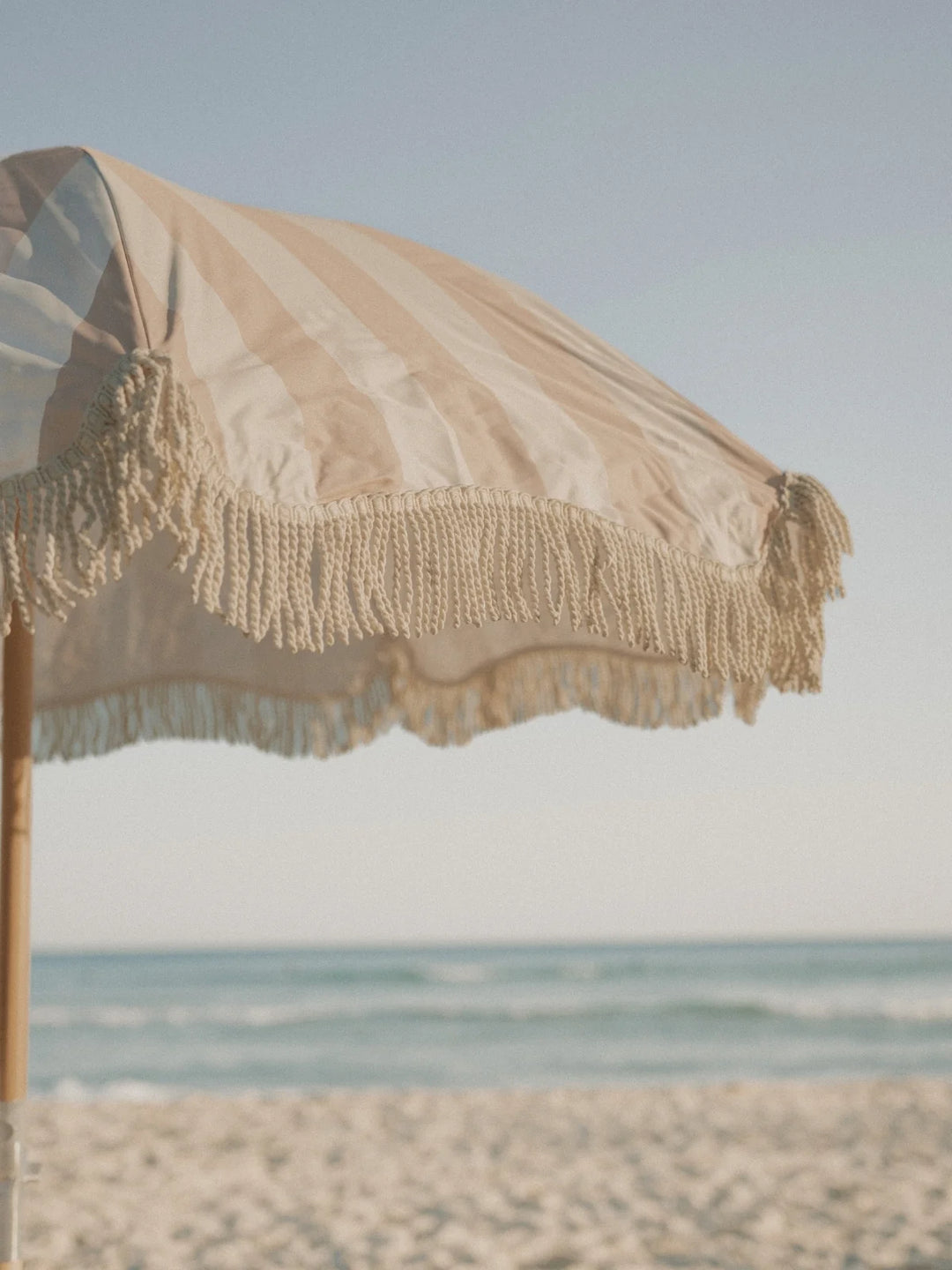 Close-up of the Sand Drift beach umbrella fringe detail swaying in the ocean breeze by House of Dune.