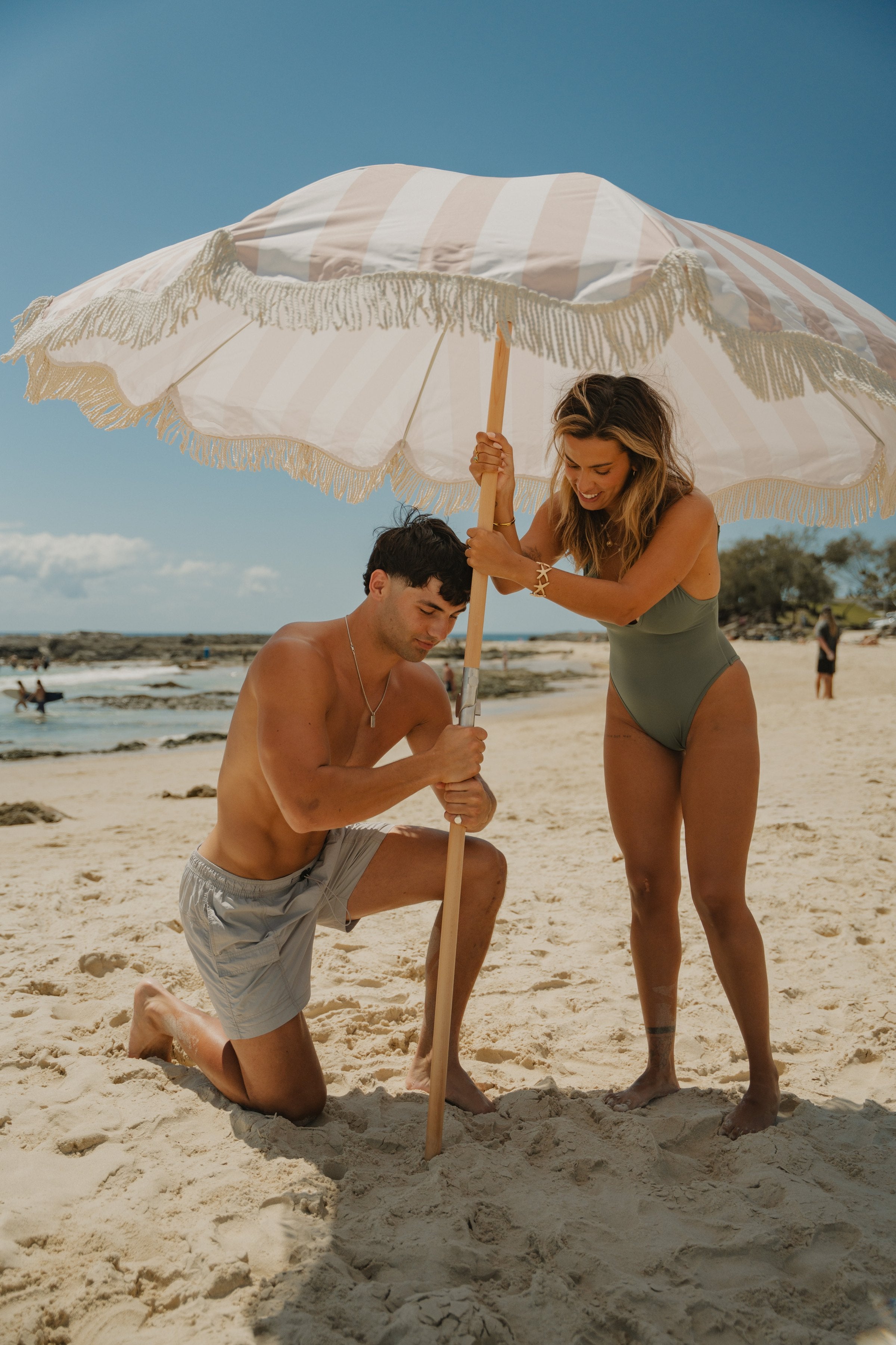 Couple setting up a Beach Umbrella on the sand