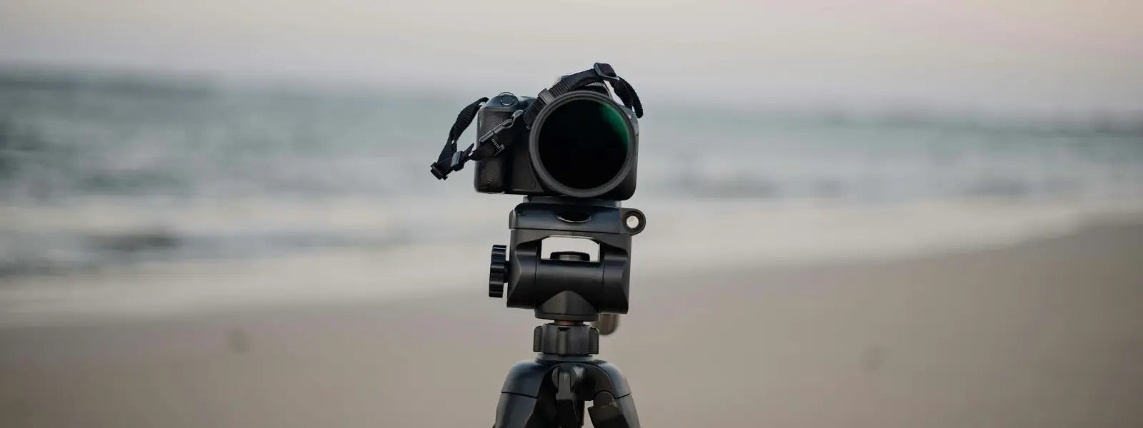 Photographer with tripod on sandy beach, press media desktop header image.