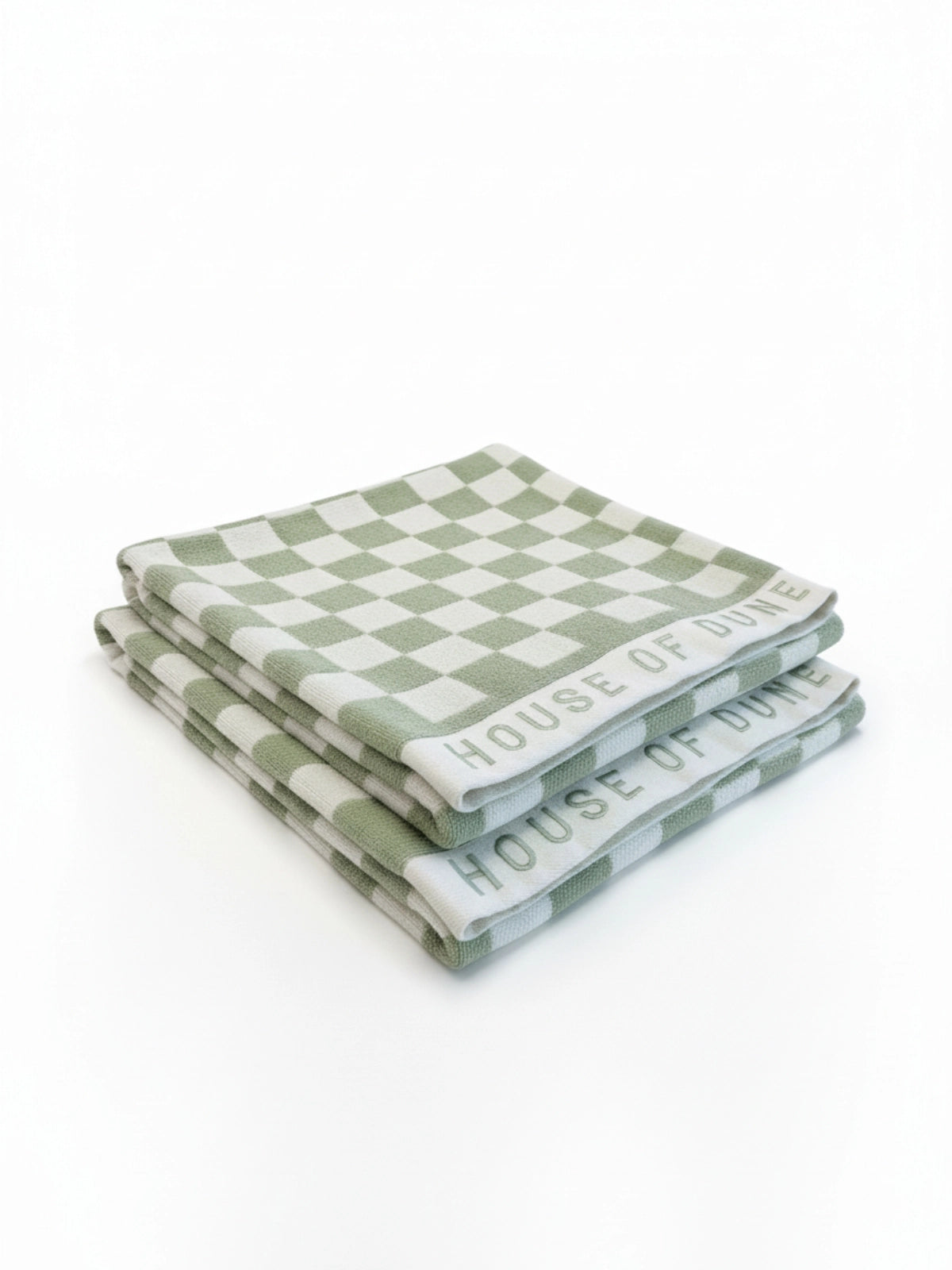 Two House of Dune Salted Sage beach towels folded and stacked, angled to show the green and white check and embroidered border.