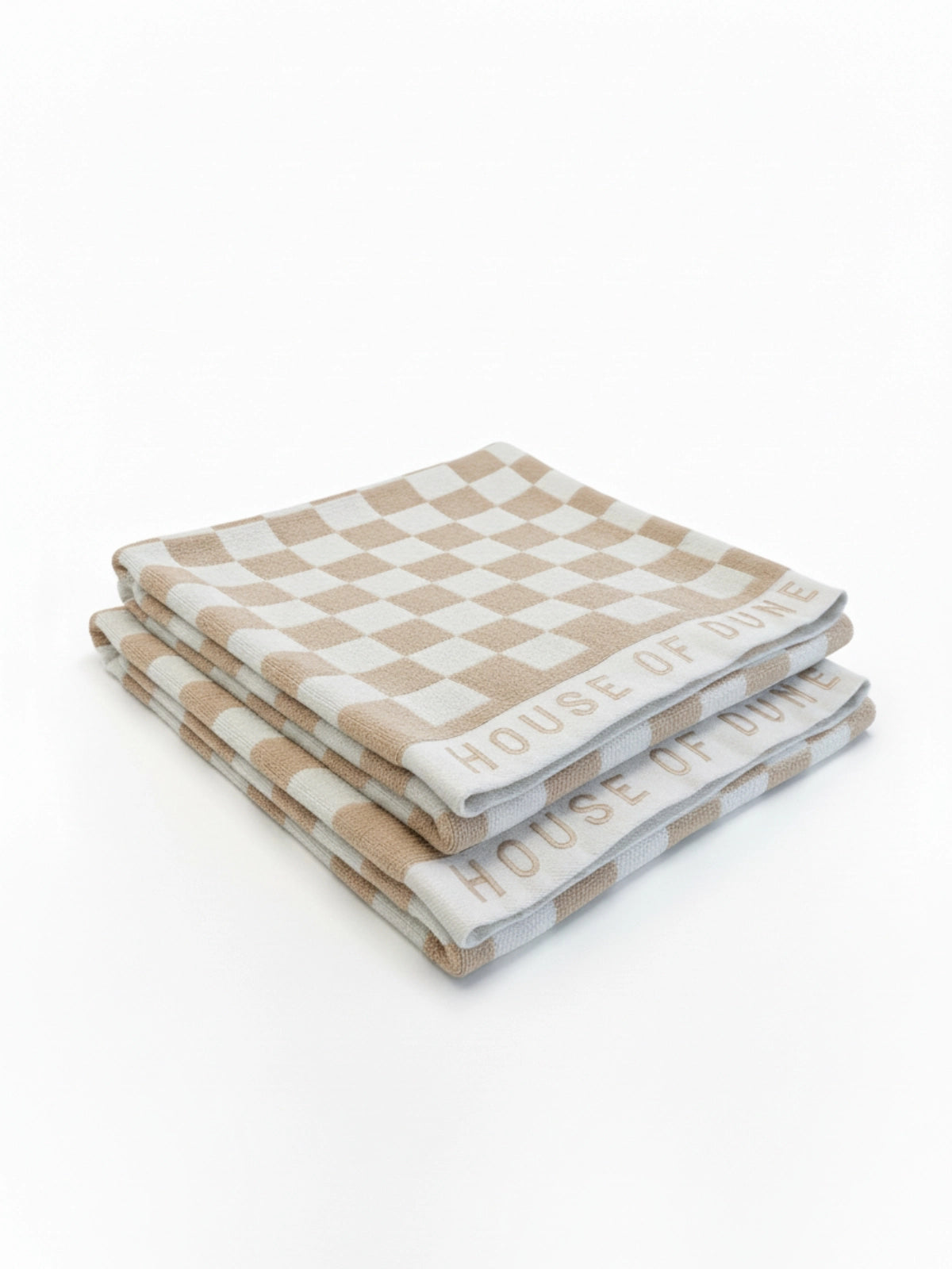 Two House of Dune Sand Drift beach towels folded and stacked, angled to show the beige and white check and embroidered border.