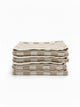 Stack of four House of Dune Sand Drift beach towels featuring a soft beige and white check pattern, folded for a refined coastal look.
