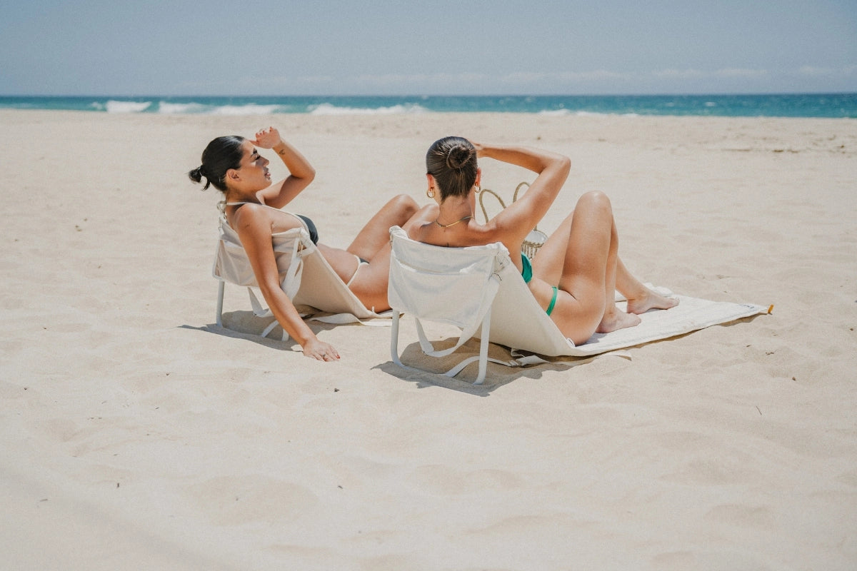 Oyster Tide and Sand Drift foldable beach loungers by House of Dune, crafted from recycled RPET, reclined on the sand with ocean views for relaxed coastal comfort.