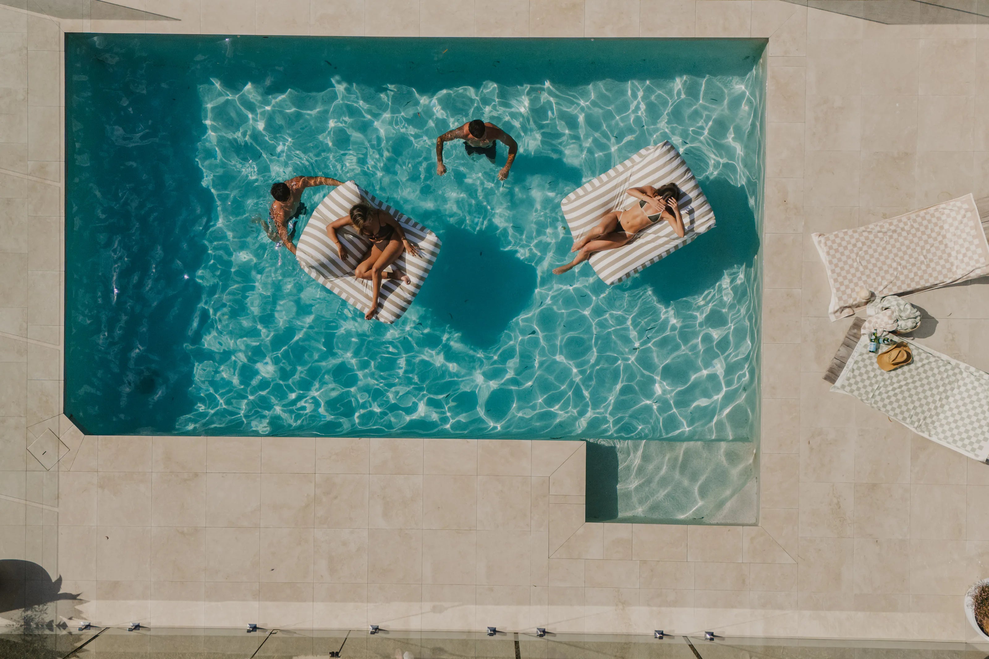 The whole pool from above, with two floating loungers and one person on each