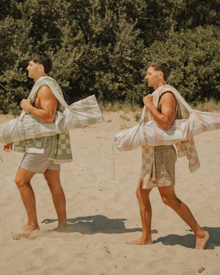 Two friends walking up the beach with their beach gear